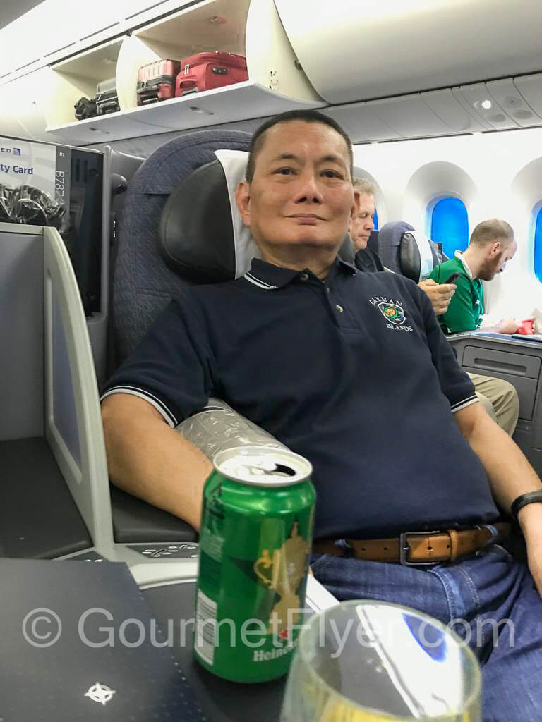 The Gourmet Flyer posing for a picture on a Business Class seat on United Airlines.