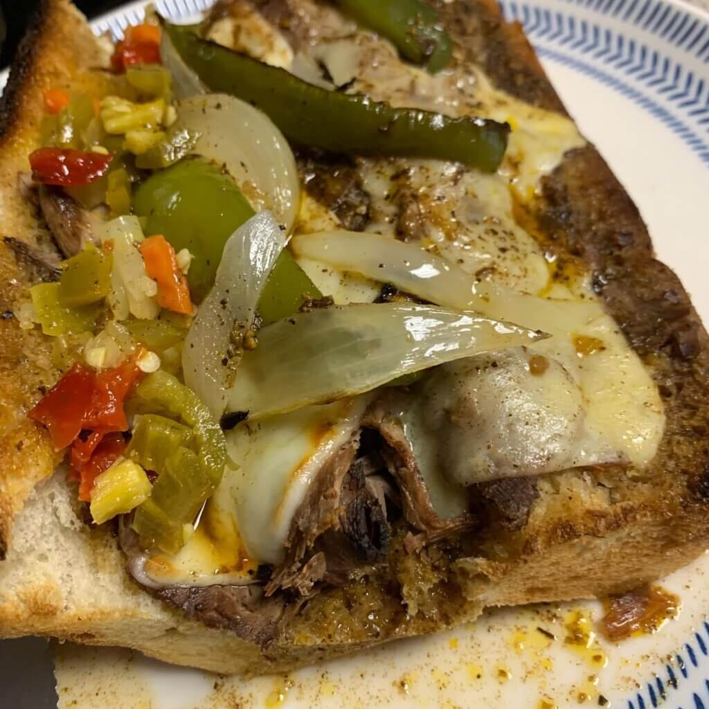 Italian beef sandwich with cheese and peppers.