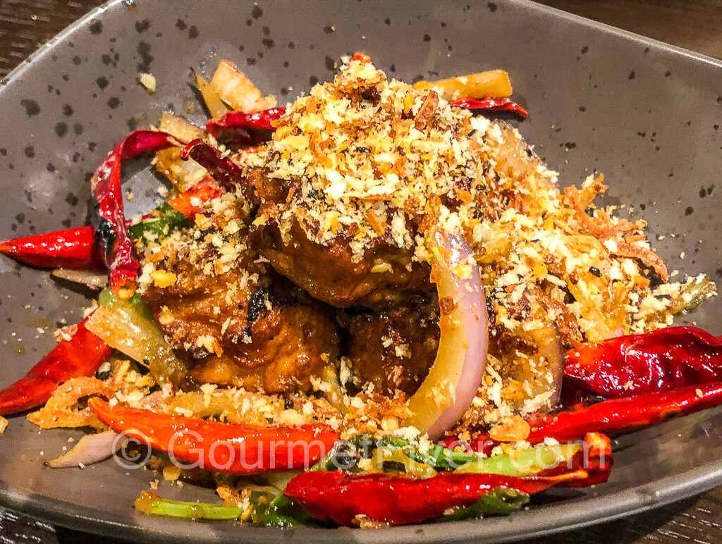 Salt and pepper siu mai garnished with garlic, peppers, and spices.