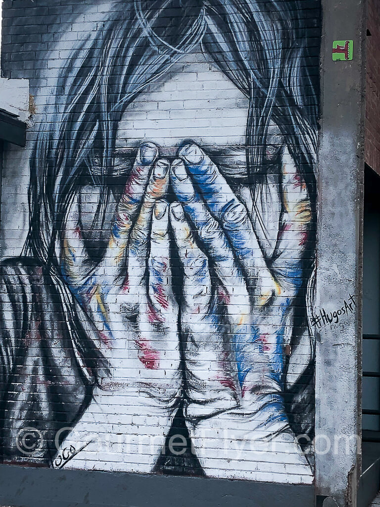 Street art of young woman covering her face