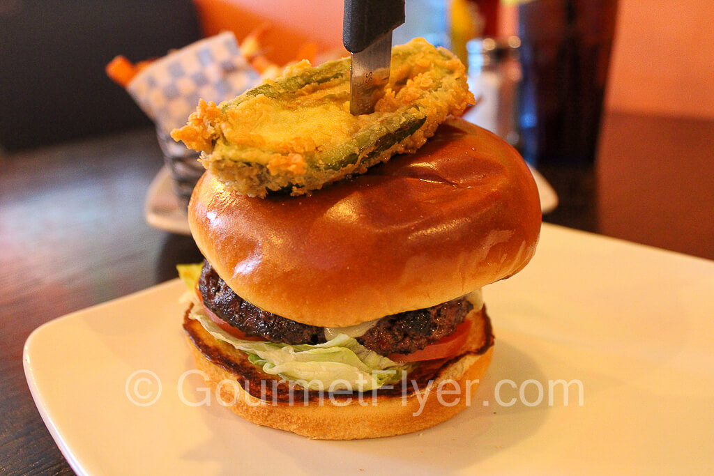Burger with fried jalapeno and a knife running through it.