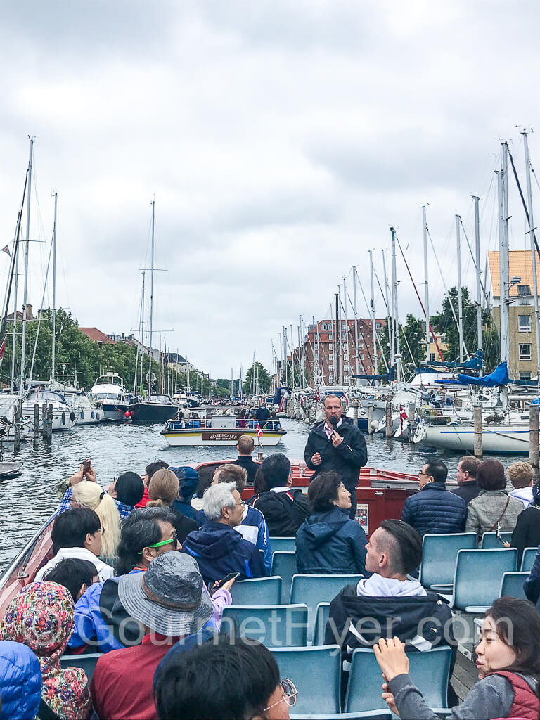 Our tour guide is at the front of the boat, talking to us with a microphone.