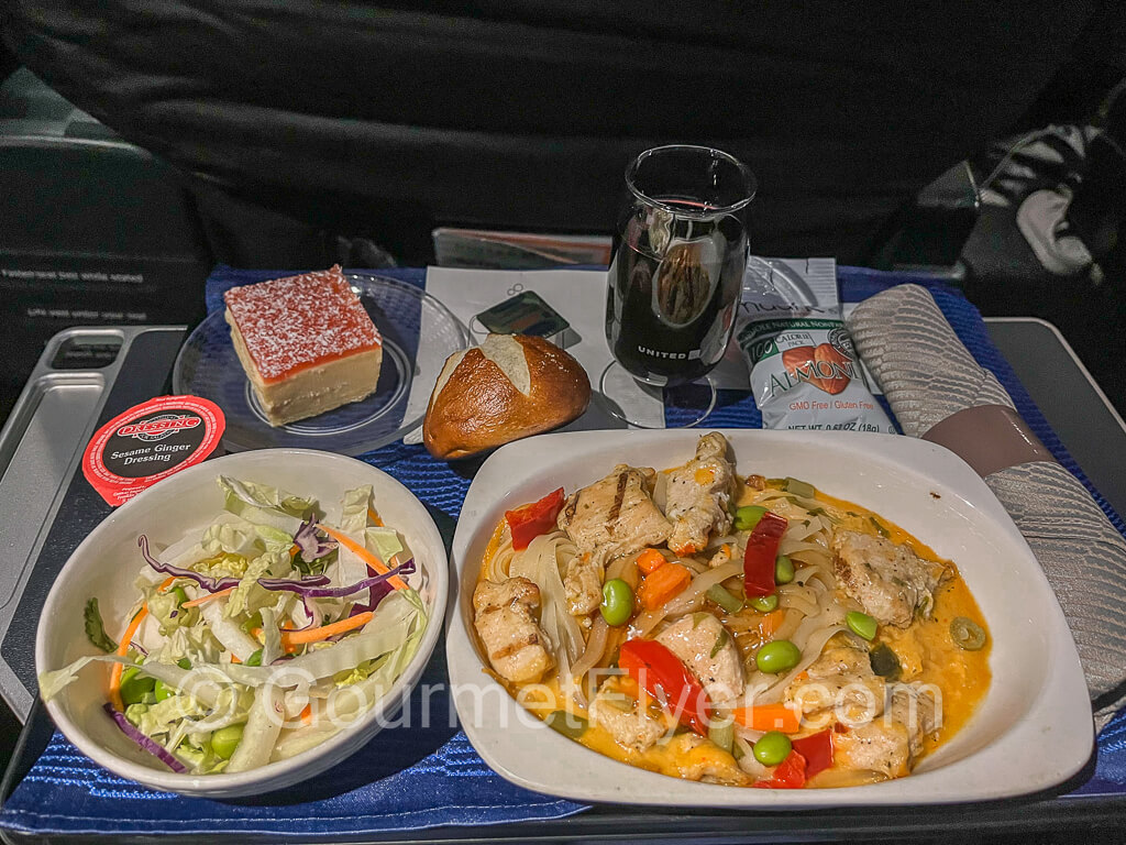 Dinner tray with Thai chicken, salad, and cheesecake as dessert.