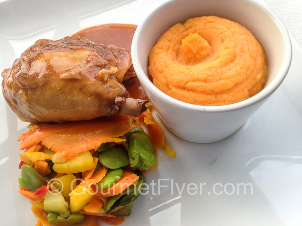 Chicken leg confit with mashed sweet potatoes and vegetables.