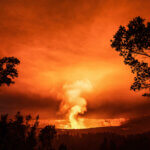 Orange glow of the volcano eruption and lava flow at night