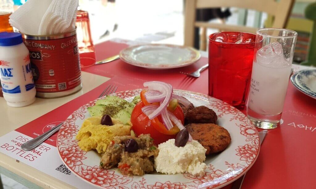 A plate of traditional Greek food with meats, salad, and rice.