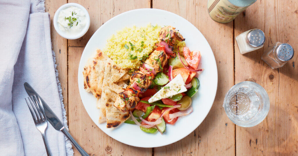 A Greek combo plate of souvlaki, rice, pita bread, and a side salad.