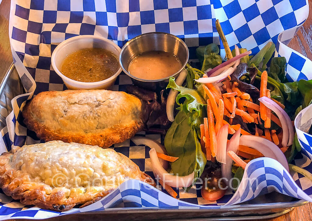 Two empanadas served with a colorful side salad.