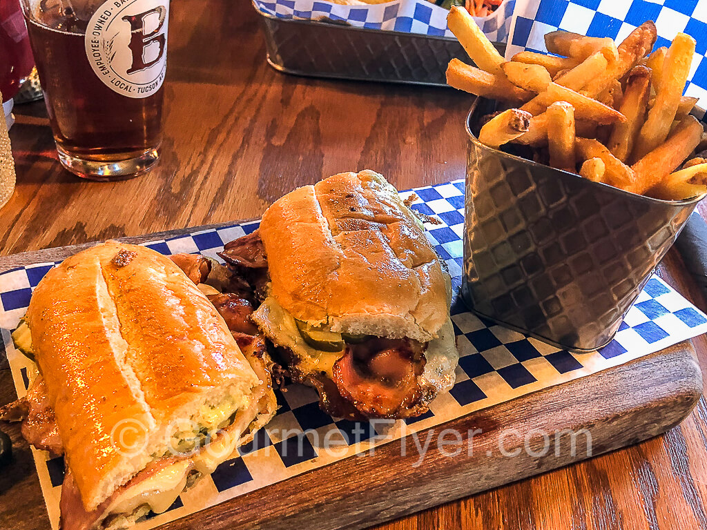 Cubano sandwich served on a plank with fries.