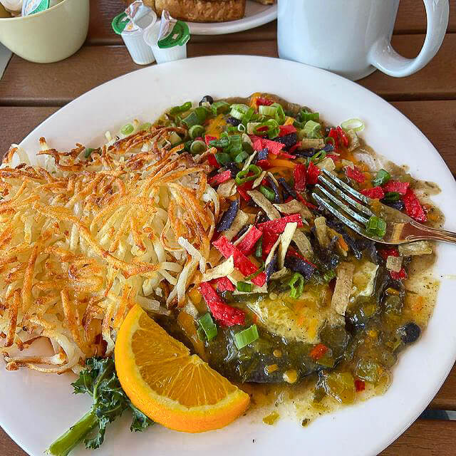A plate of blue corn huevos rancheros served with hash browns.
