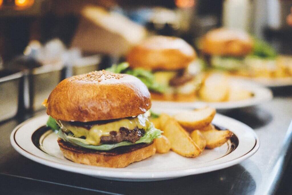 A hamburger topped with melted cheese is served on a plate with fries.