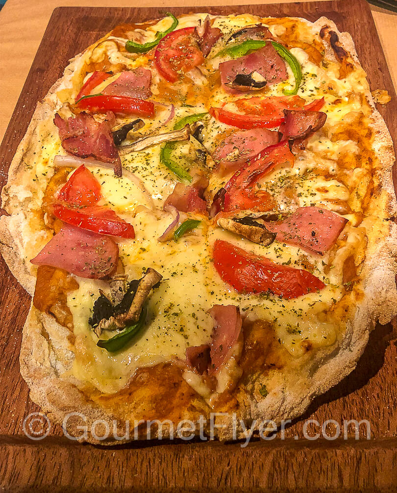 A flatbread with ham, mushrooms, tomatoes, and peppers.