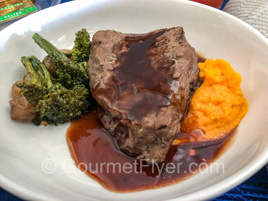 Plate of beef rib meat with broccoli and sweet potatoes.