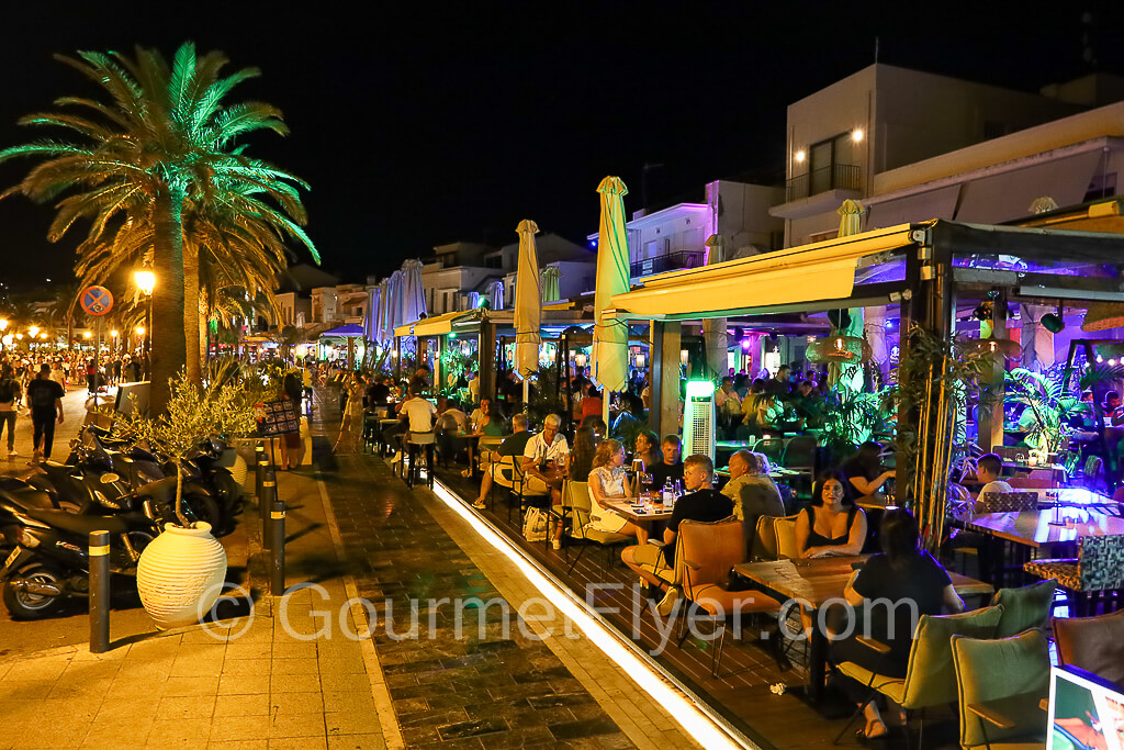 Street lined with lively bars with colorful lightings.