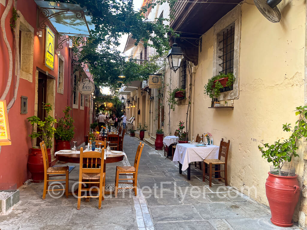 Tabels from a taverna line the side of an alley.