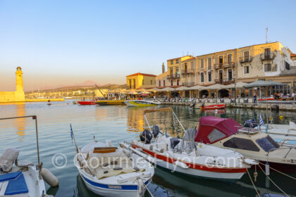 Rethymno Itinerary - Venetian Harbor during sunset, with tour boats in the foreground and the lighthouse in the background.