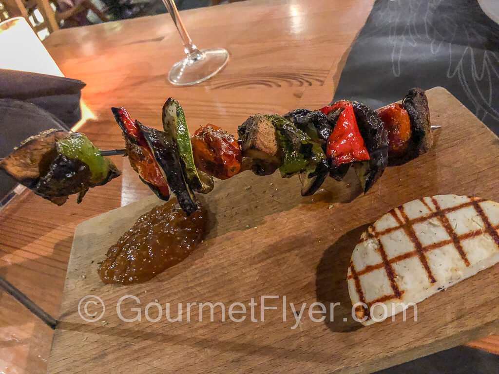 A skewer with red and green peppers and other veggies.