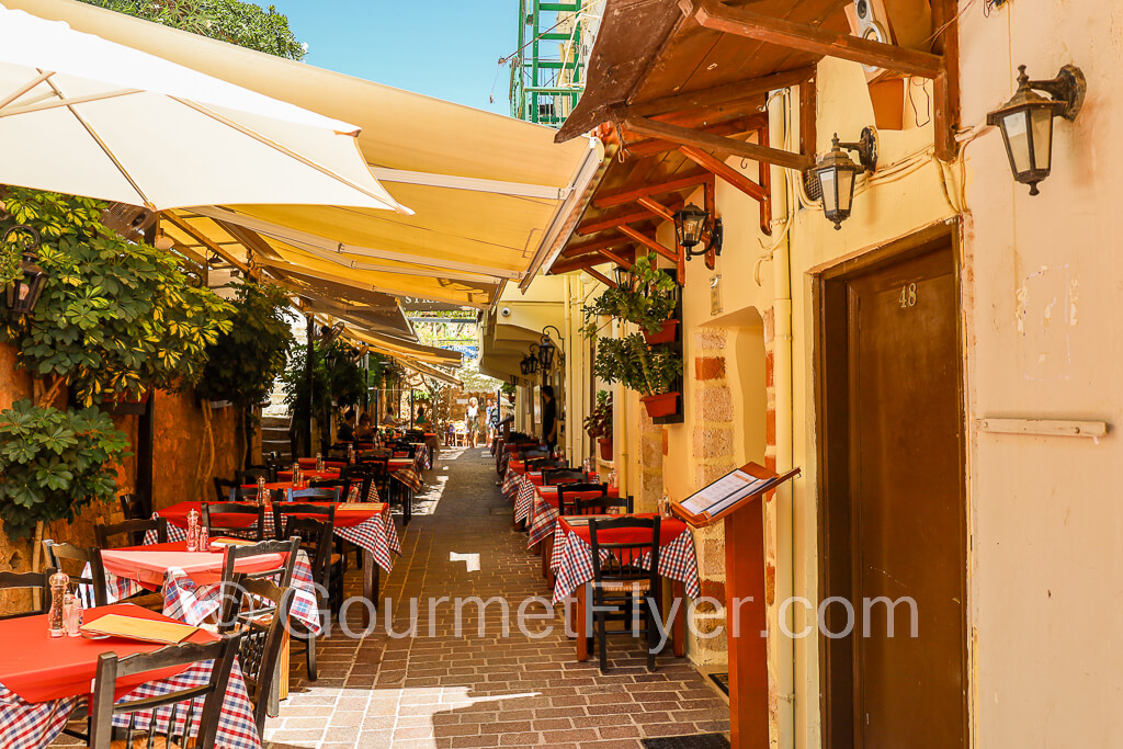 Tables from the restaurant with red tablecloths line the sides of an alley in Old Town.