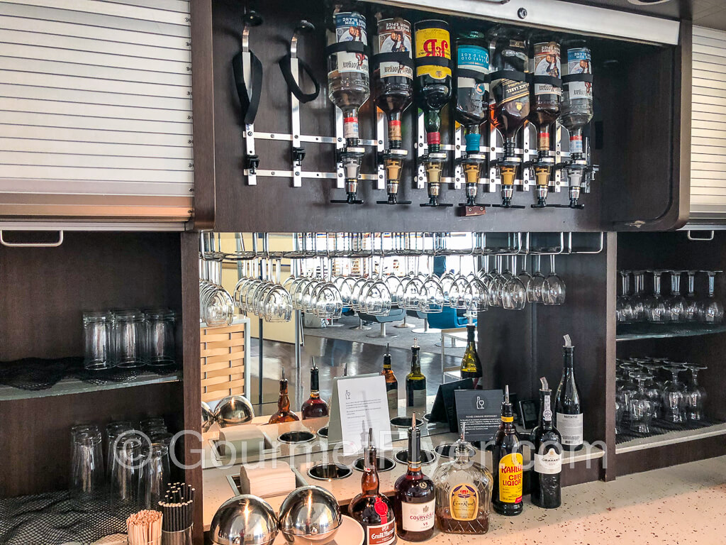 The self-served alcoholic beverage counter with some bottles sitting on the counter and some upside down on a pouring machine.