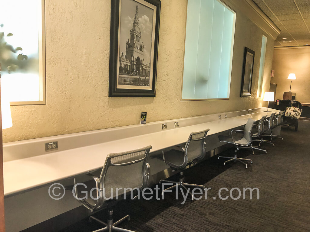 A long work bench with chairs is placed against the wall. Plenty of power sockets are on the bench.