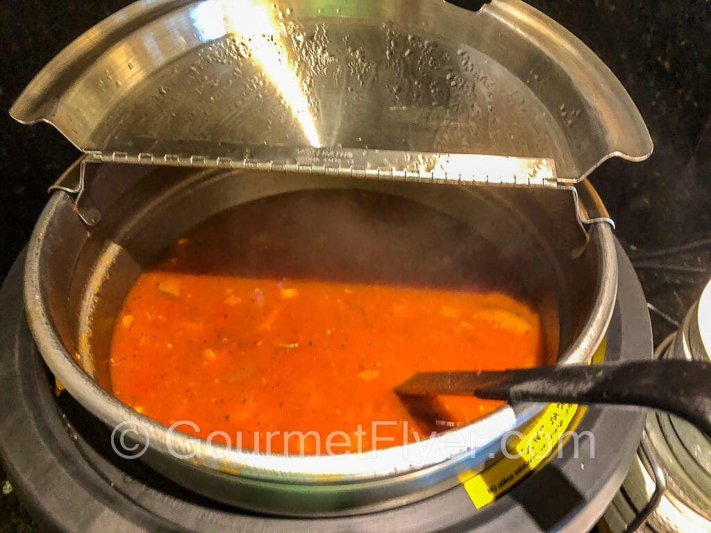 A pot of vegetarian Minestrone soup with a soup ladle halfway into the pot.