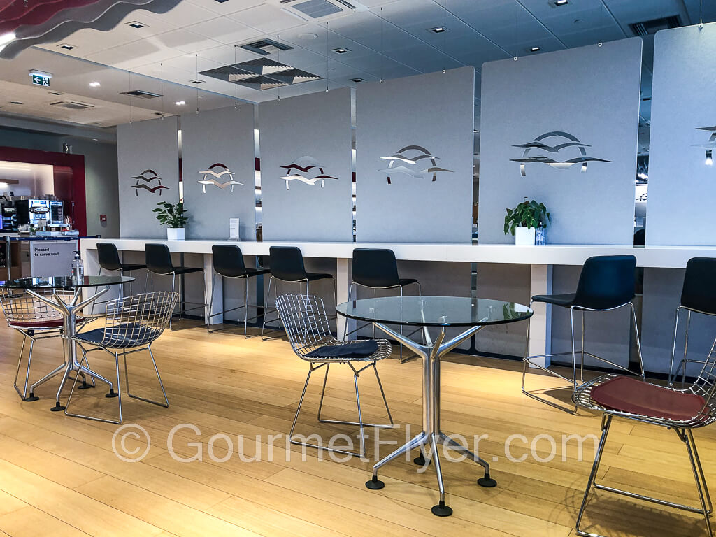 Round dining tables with chairs lie adjacent to a long counter with highchairs.