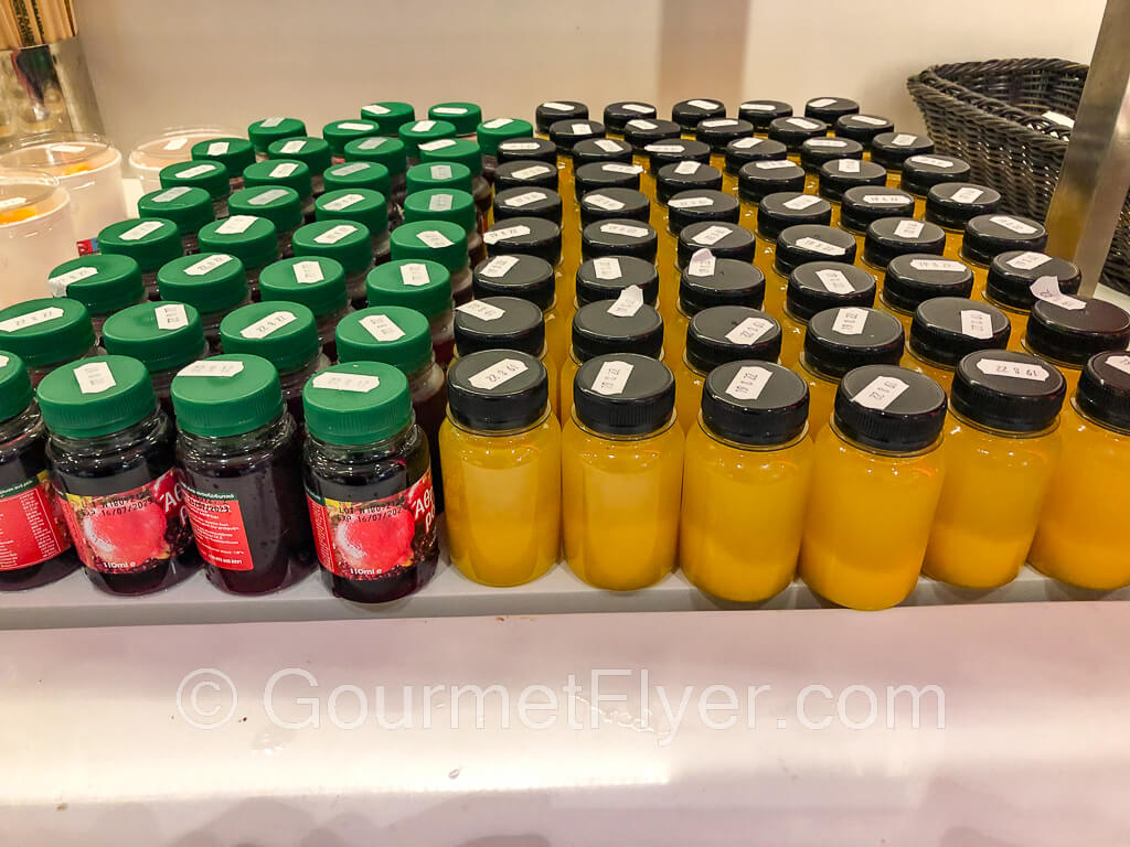 Rows of fresh juice in small bottles sit on top of the buffet counter.