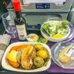 Review of United's Premium Plus Premium Economy features a dinner with chicken breast and vegetables and accompanied by a small bottle of red wine.