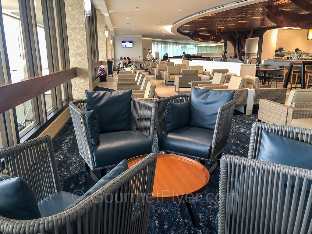 A set of blue sofas around a wooden tea table near the window, with many other sets of lounge chairs in the background.