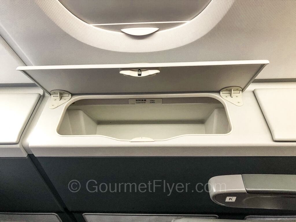 A storage compartment to the right of a window seat with its lid opened.