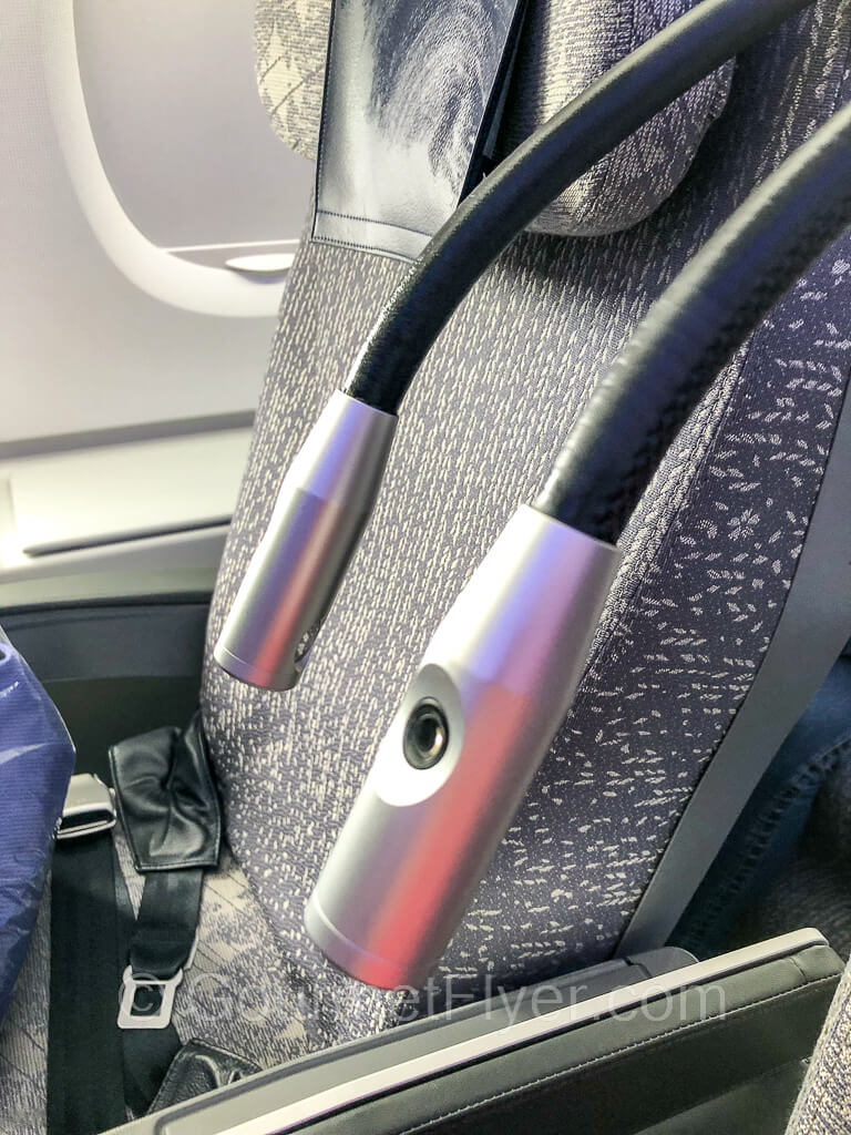 A pair of reading lights with adjustable bendable wire holders are extended between two seats.