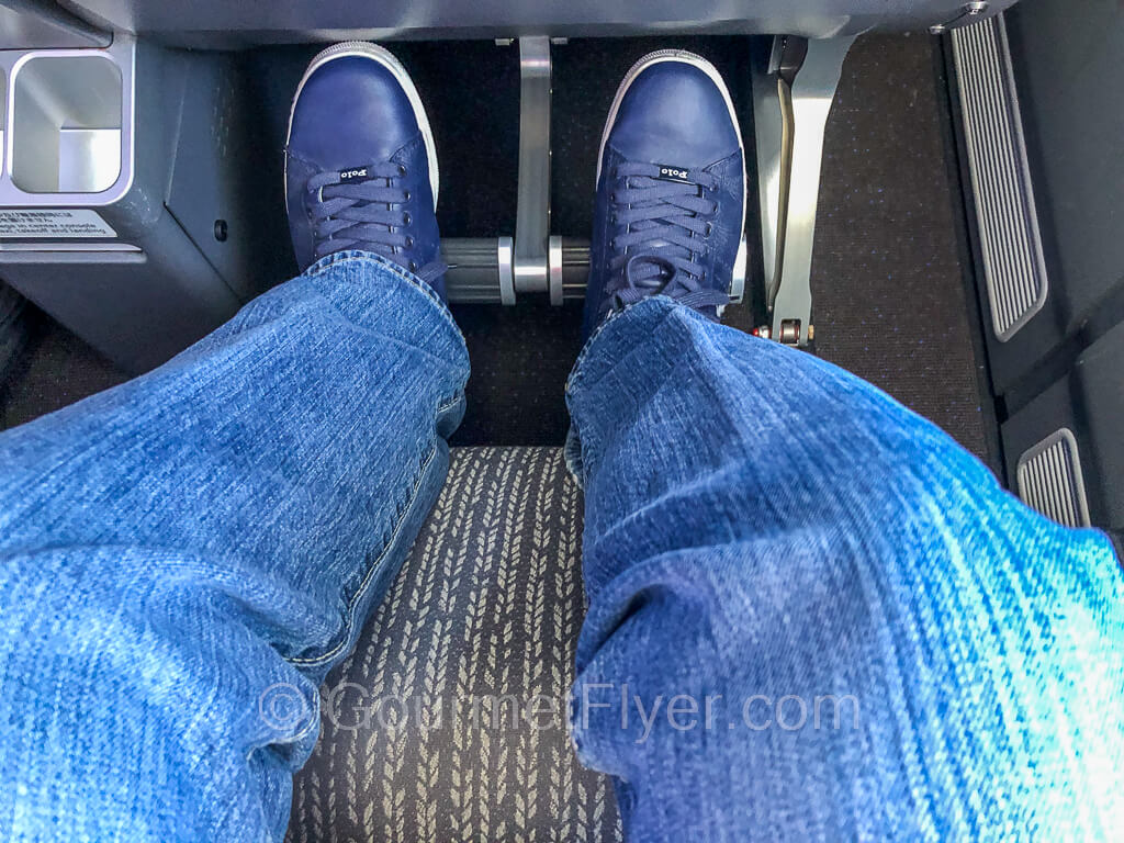 A person wearing blue jeans and blue Polo shoes is resting his leg and feet on the extended leg rest and footrest.