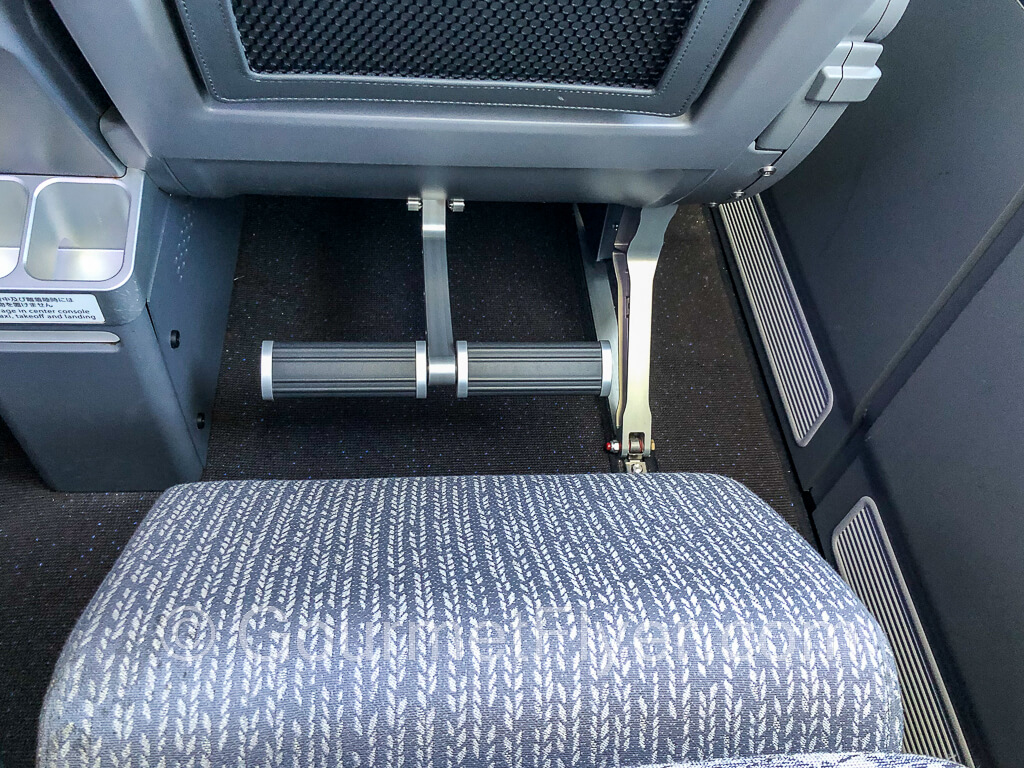 A premium economy seat with the leg rest fully extended and the footrest pressed halfway down.