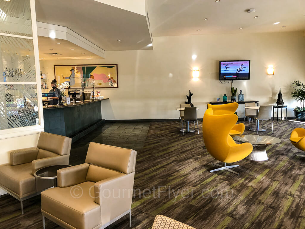 Sofas and a set of 3 small round dining tables for two are placed near the bar area.