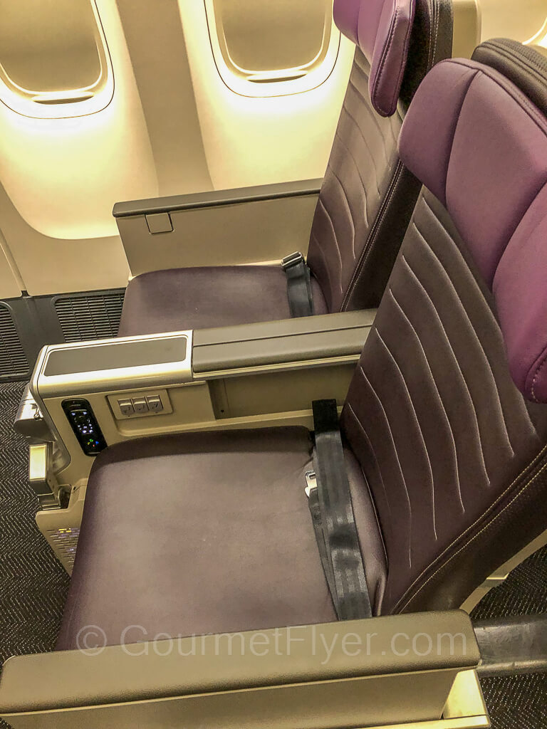Purple color United Premium Plus seats 22K and 22L on the right side of the plane, with the seatbelts neatly folder.