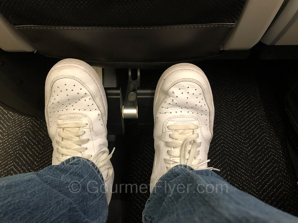 My feet in white tennis shoes resting on the footrest.