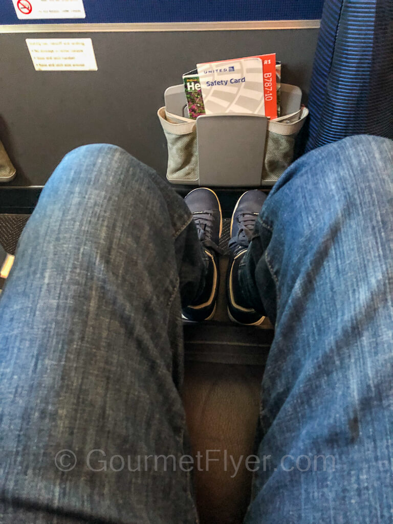 A person wearing blue jeans rests his legs and feet on the leg rest.
