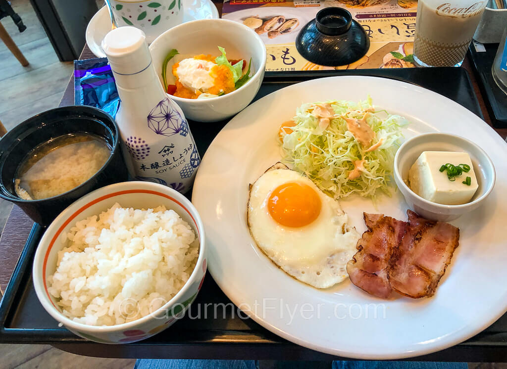 A plate with one egg, ham, shredded lettuce and tofu is accompanied by a bowl of rice and miso soup.