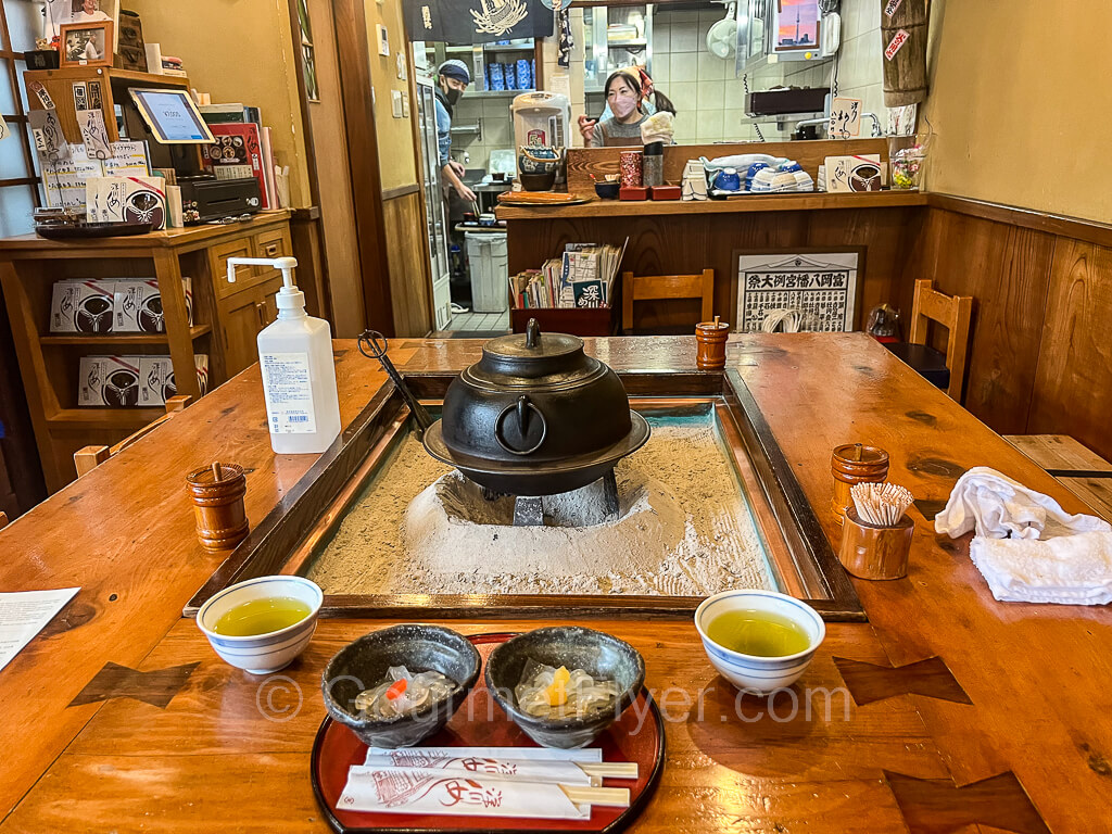 A large square Japanese style table is in the foreground with the kitchen in the background.