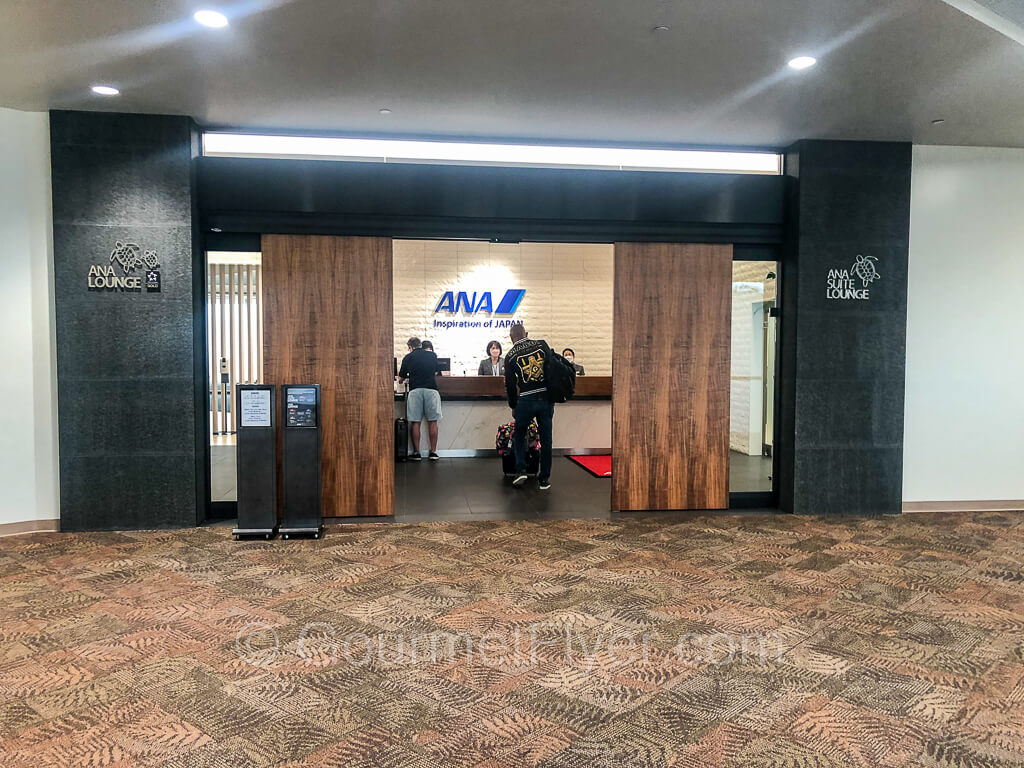 The entrance to the ANA Lounge with the front door opened showing the reception desk with agents inside checking in customers.