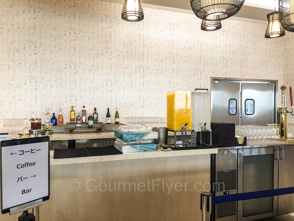 A sign showing coffee to the left and bar to the right stands in front of the bar with bottles of liquor in the background.