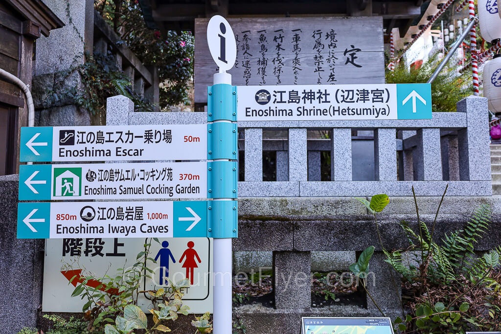 A sign that gives directions to the shrine by taking the stairs or the escalator, with arrows pointing to the right directions.