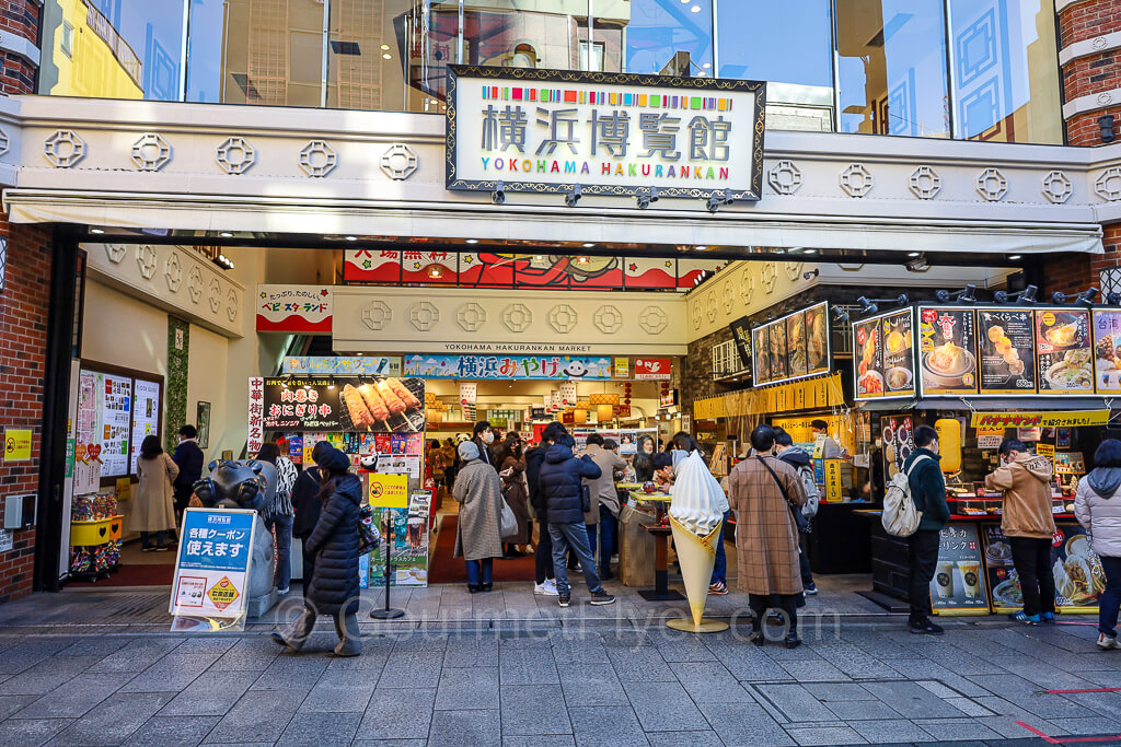 The entrance to a large souvenir store is full of people browsing at various stations.