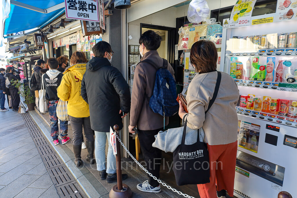 People stand in line in front of a popular restaurant.