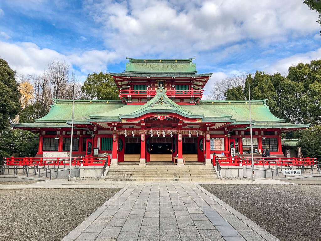 A majestic looking shrine with bright red pillars and the traditional green tiled roof.