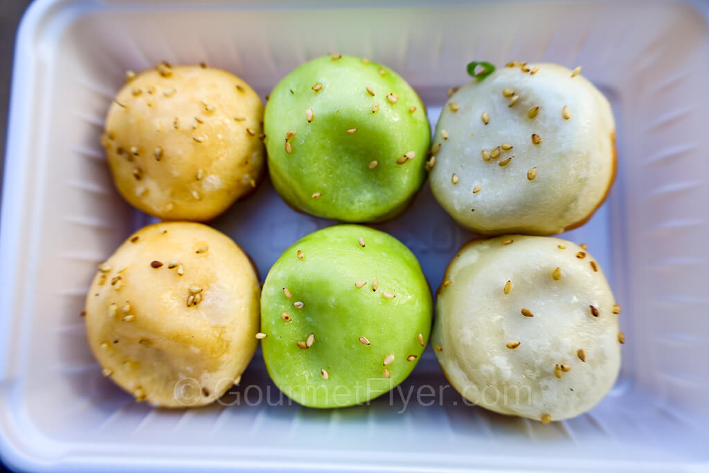 A container with 6 dumplings in 3 colors. From left to right, yellow, green, and white -- which are seafood, veggies, and pork flavors.