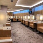Review of the ANA Lounge in NRT Airport features a row of wide and comfortable sofas with reading lamps and separated by coffee tables with glass partitions.