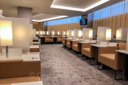 Review of the ANA Lounge in NRT Airport features a row of wide and comfortable sofas with reading lamps and separated by coffee tables with glass partitions.