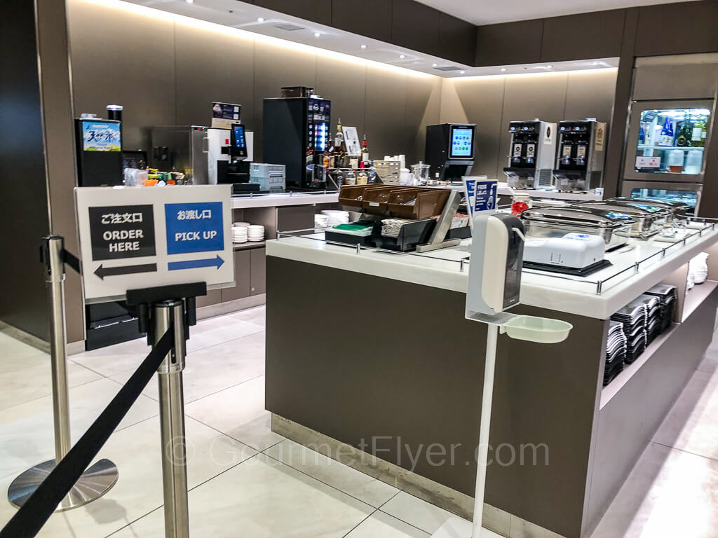 The food and beverage stations and islands are all located in one area with a sign pointing to the ordering line from the kitchen.