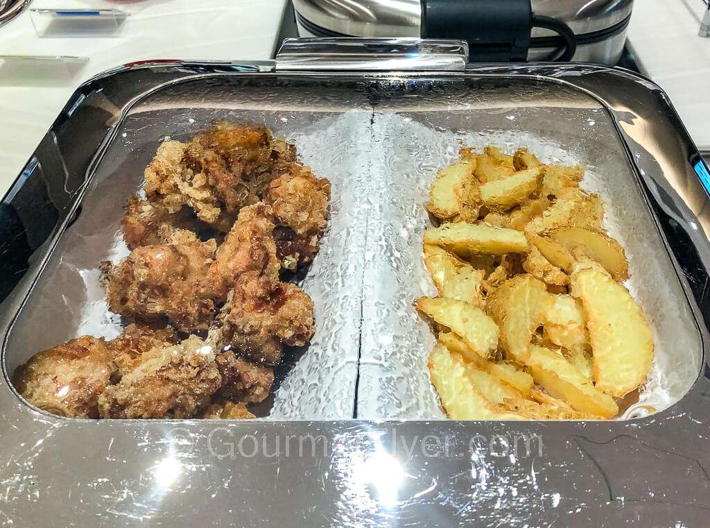 A hot tray with fried chicken on the left and French fries on the right.
